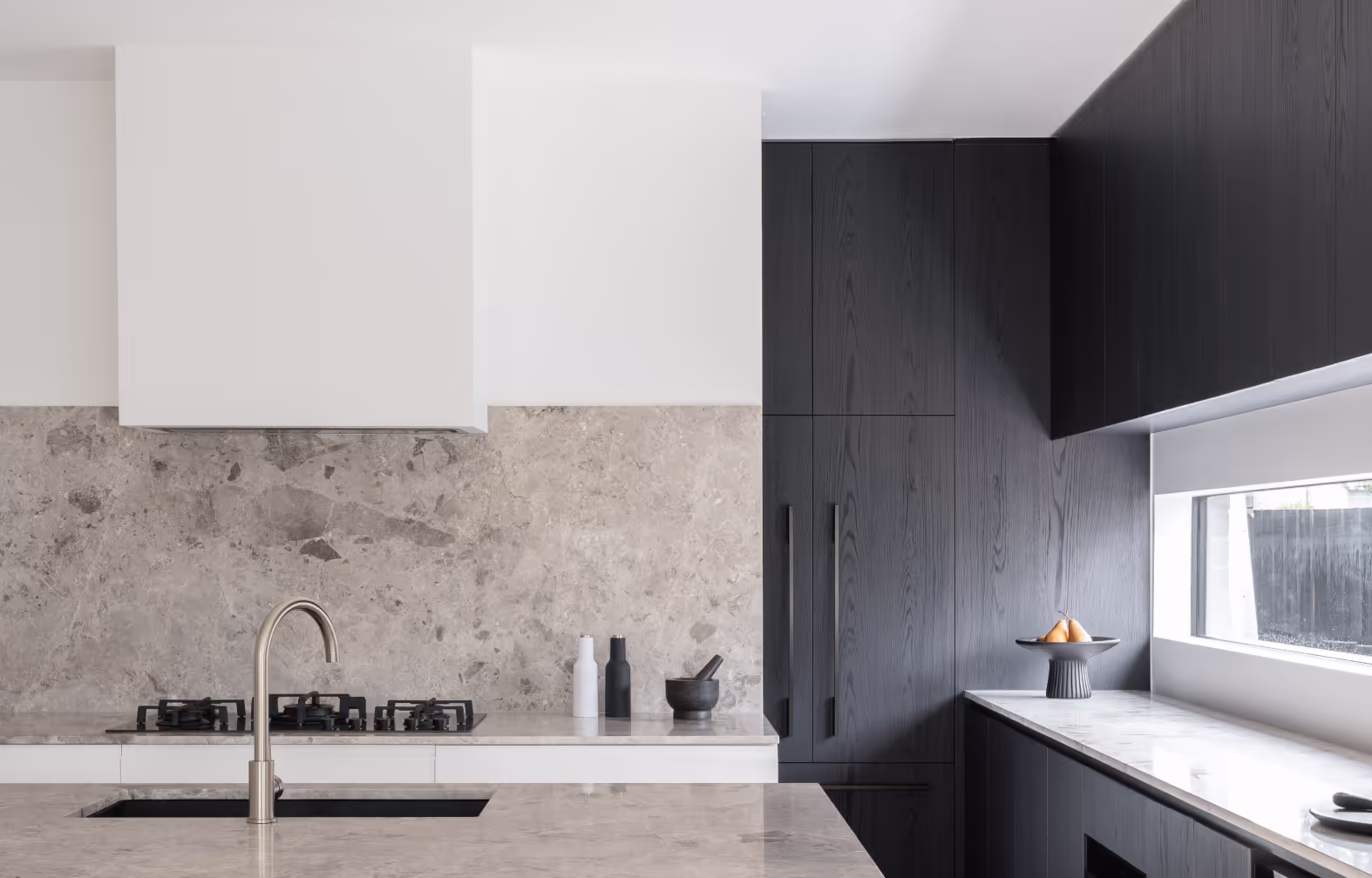 Natural stone splashback and black cabinetry in custom home by Yarraville builder